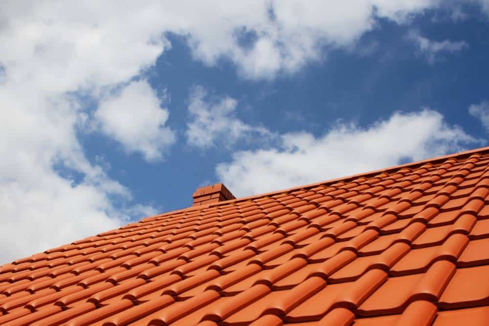 Clay tile roof under clear skies in need of minor repair