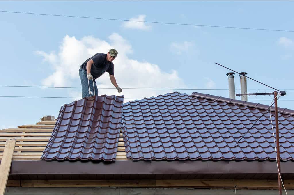 Roofer installing new metal panels